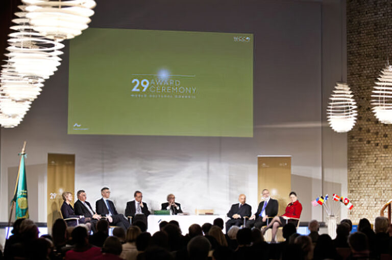 2012 WCC ceremony at Aarhus University, with attendees and speakers on stage.